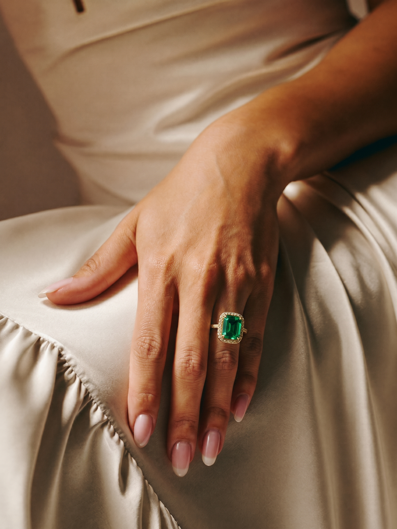 Anel de esmeralda cushion em ouro 18k JLópez · mão feminina sobre seda marfim